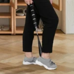Personne utilisant un chausse-pied à long manche pour enfiler ses chaussures.