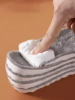 S91204bbea5da4e82aa942197ec9dbed2o.webp Gros plan sur des pantoufles douces et superposées ; main testant la texture de la peluche.