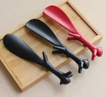 Chausse-pieds originaux en forme de pattes d'animaux, rouge et noir, sur un plateau en bois.