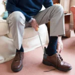 Personne âgée utilisant un chausse-pied pour mettre ses chaussures marron.