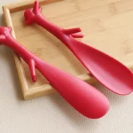 Chausse-pieds rouges originaux en forme de cerf sur un plateau en bois.