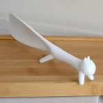 Spatule à riz blanche en forme de chat sur une planche à découper.